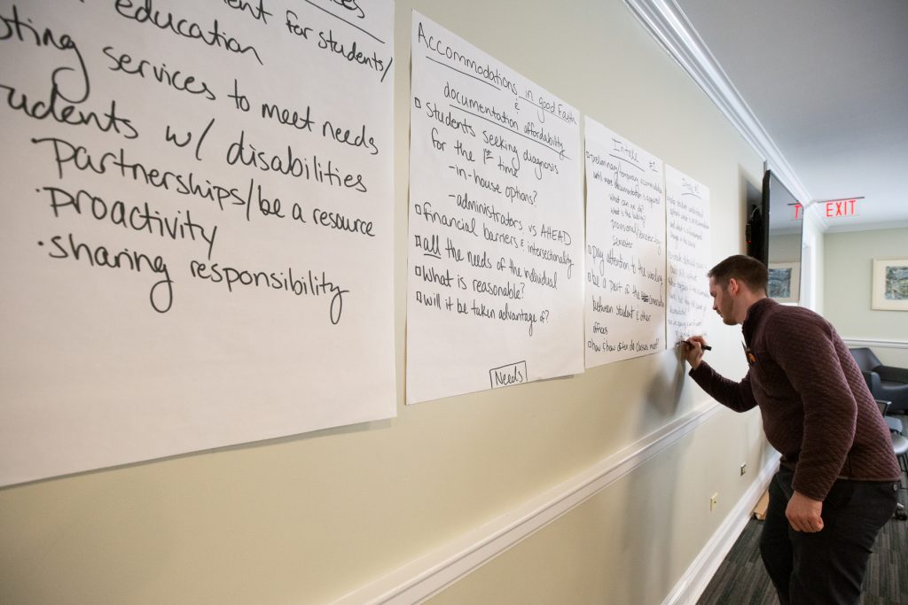 man using a marker to write on a giant post-it note positioned on the wall